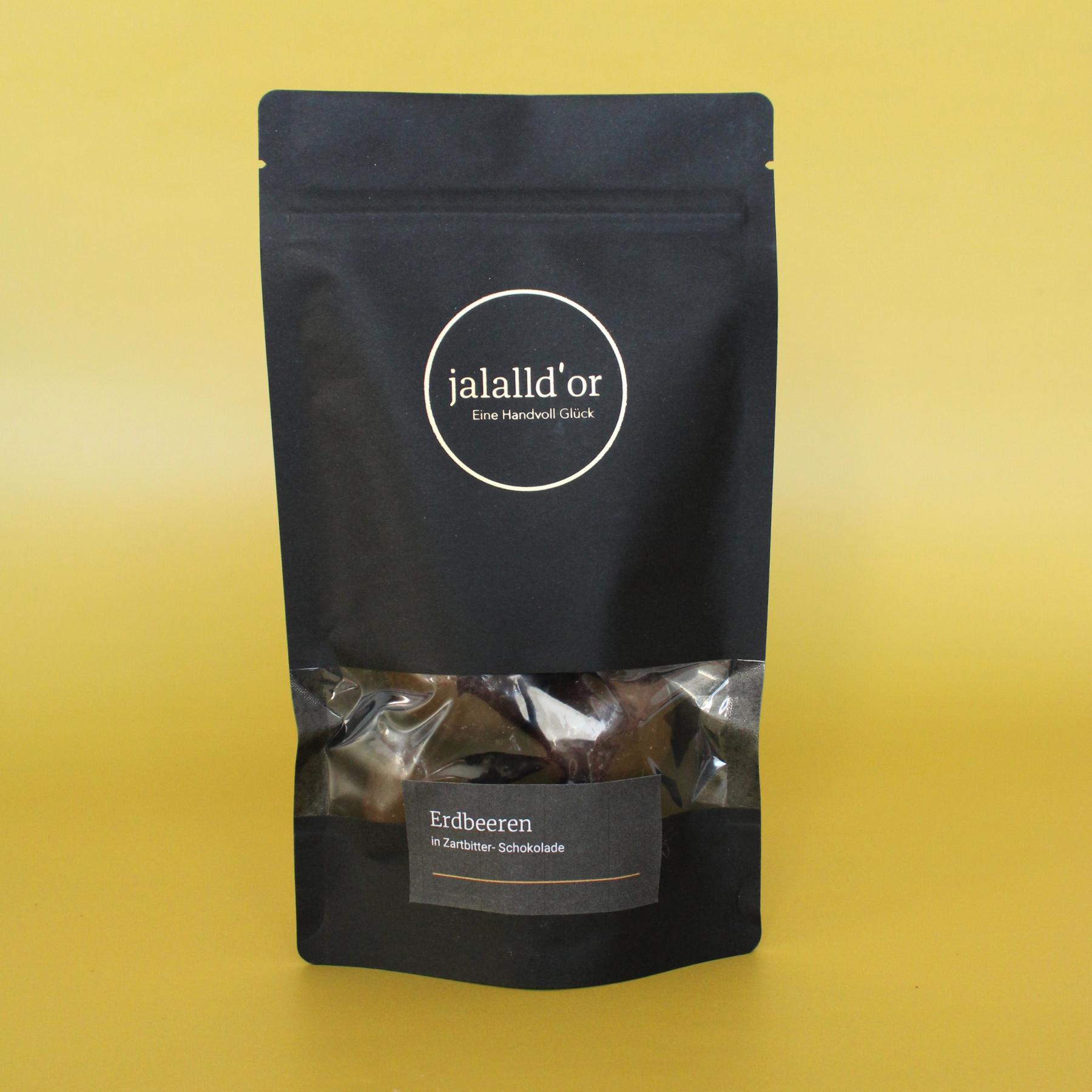 schwarze Geschenkpackung mit schoko erdbeeren vor goldenem Hintergrund