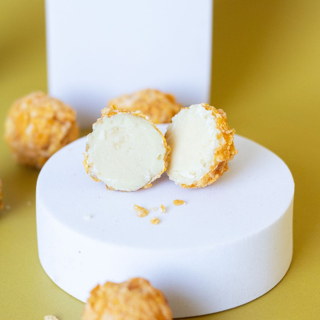 Lemon Trüffel Praline  helle Praline aufgeschnitten auf rundem weißen Podest