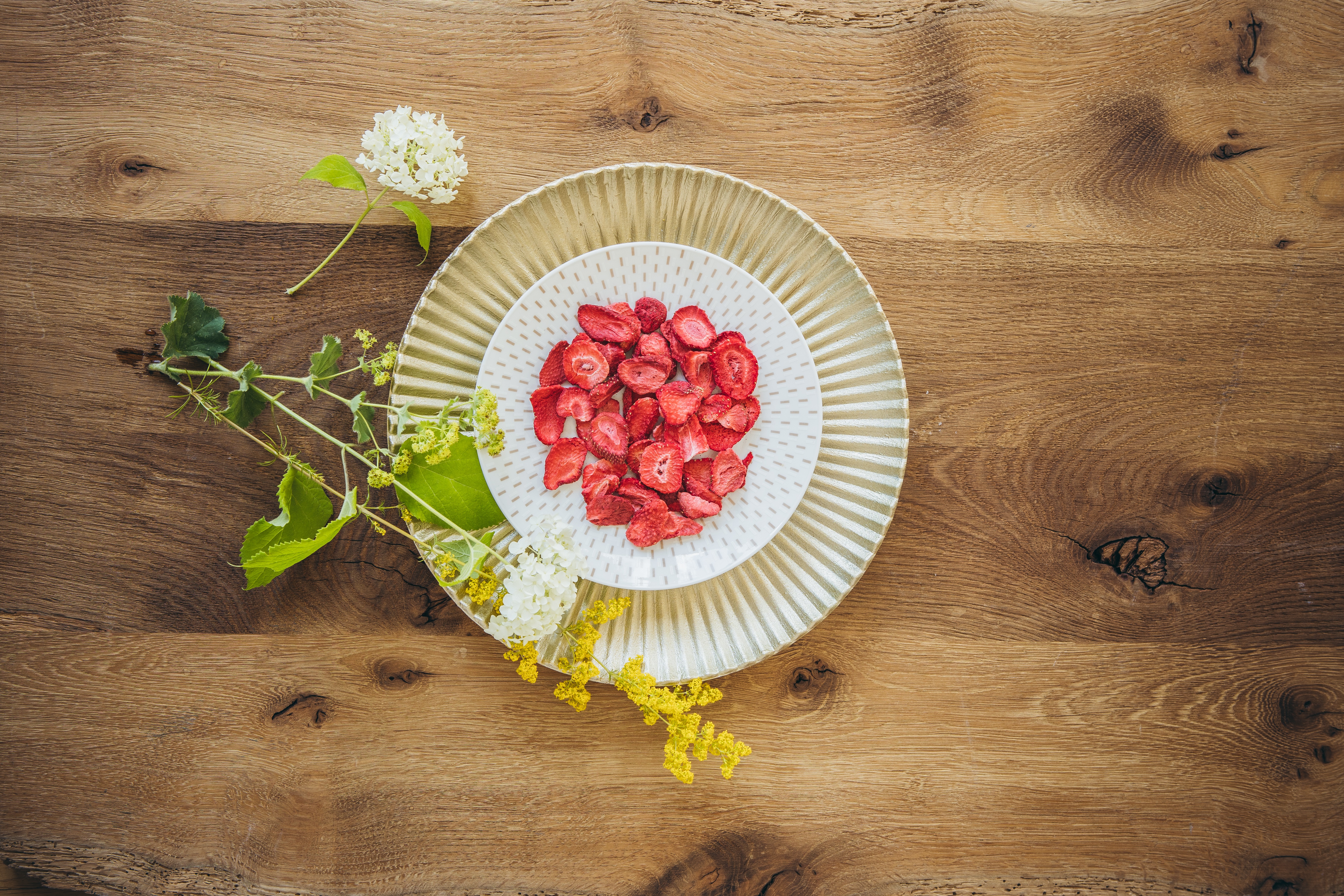 gefriergetrocknete Erdbeeren auf Teller auf Holzuntergrund