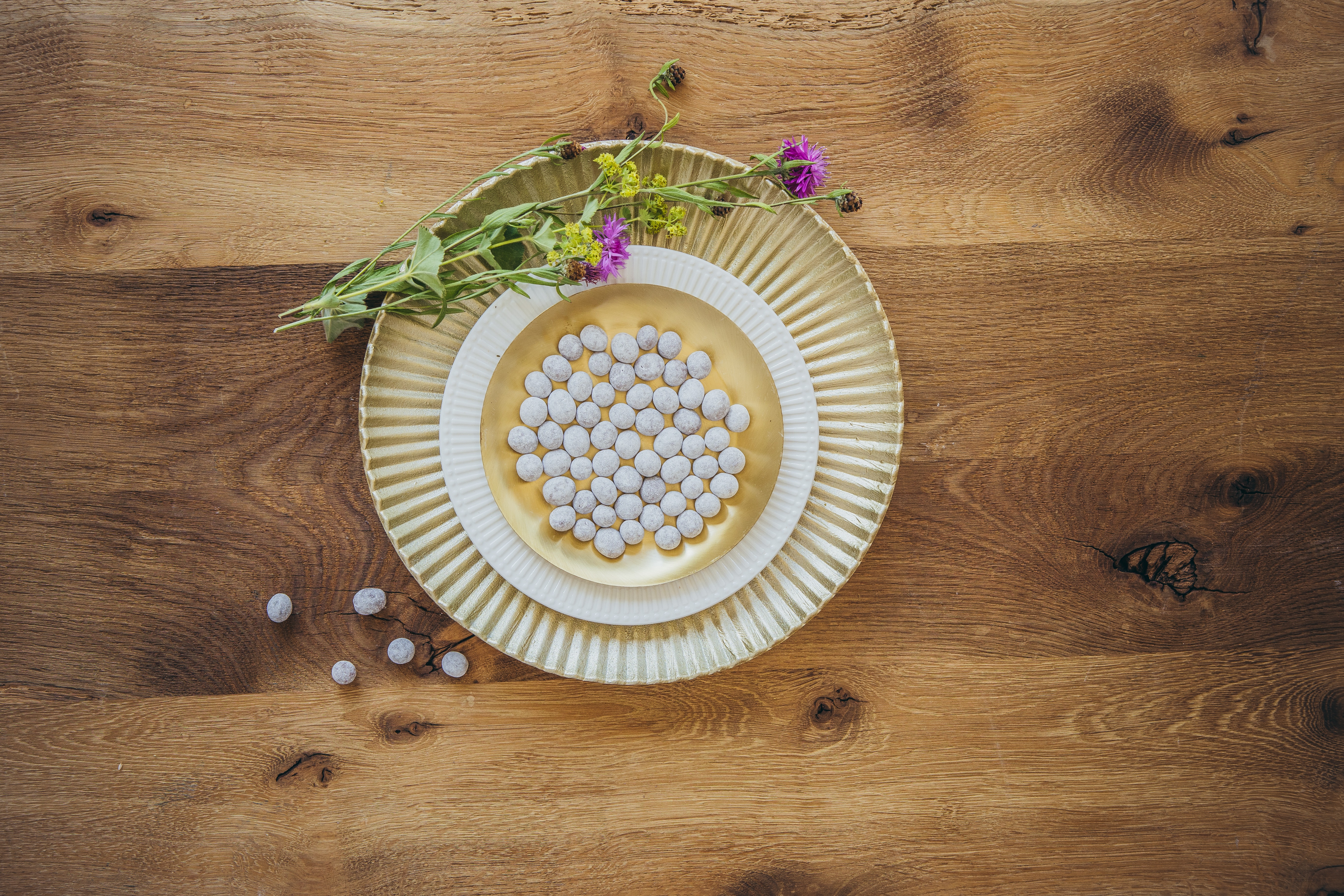 schokolierte Kaffeebohnen auf gold Tellern auf einem Holzboden