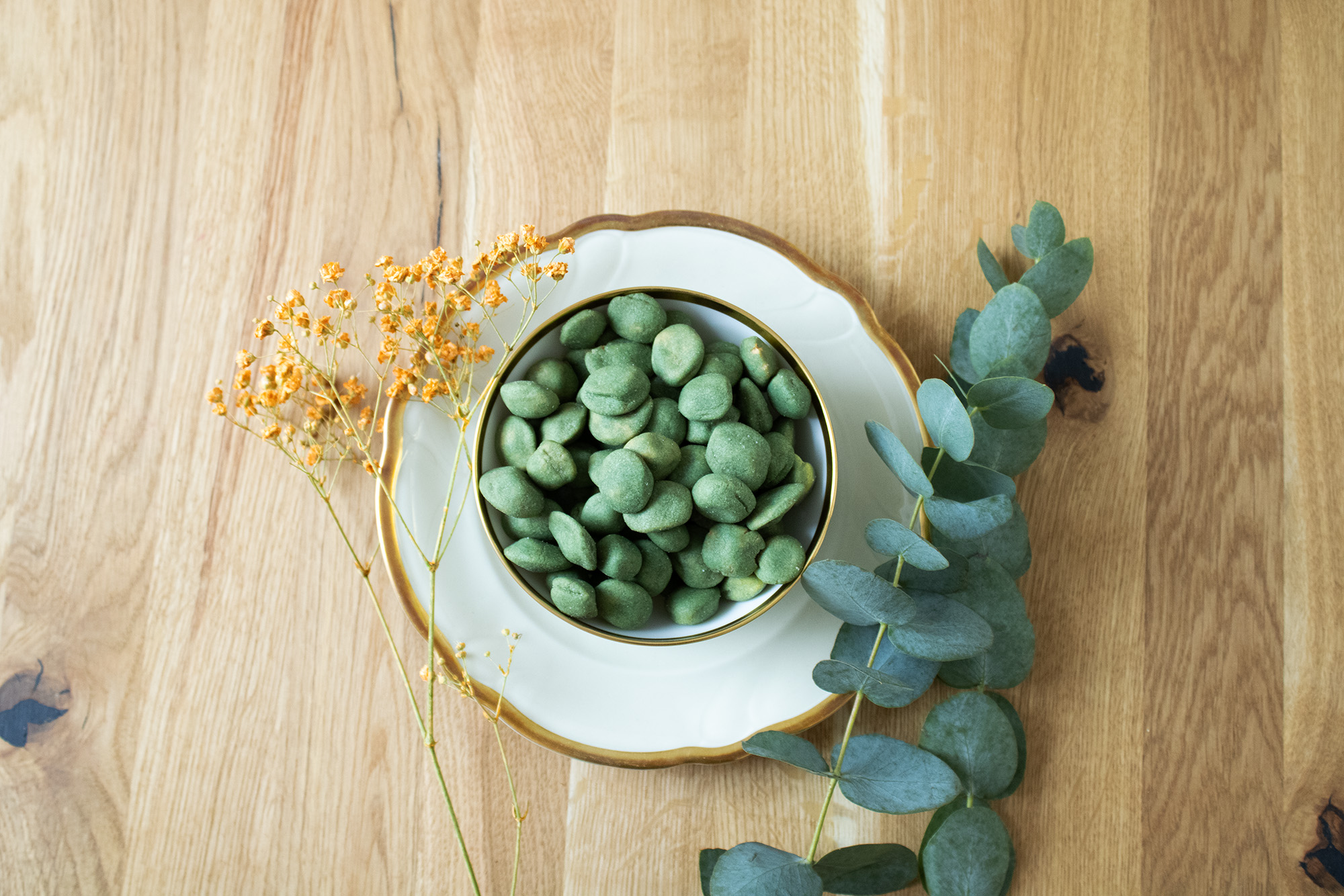 Wasabi Nuesse Ufoform in einer Schale auf weißem Teller mit Blumen