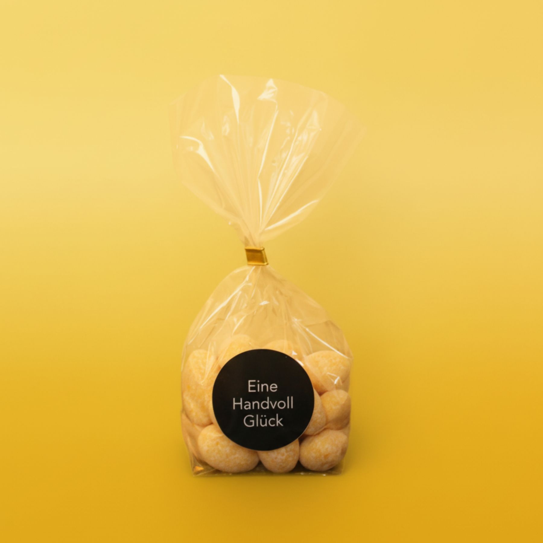 Cellophantuete mit gelben Zitronenmandeln und goldgelbem Hintergrund