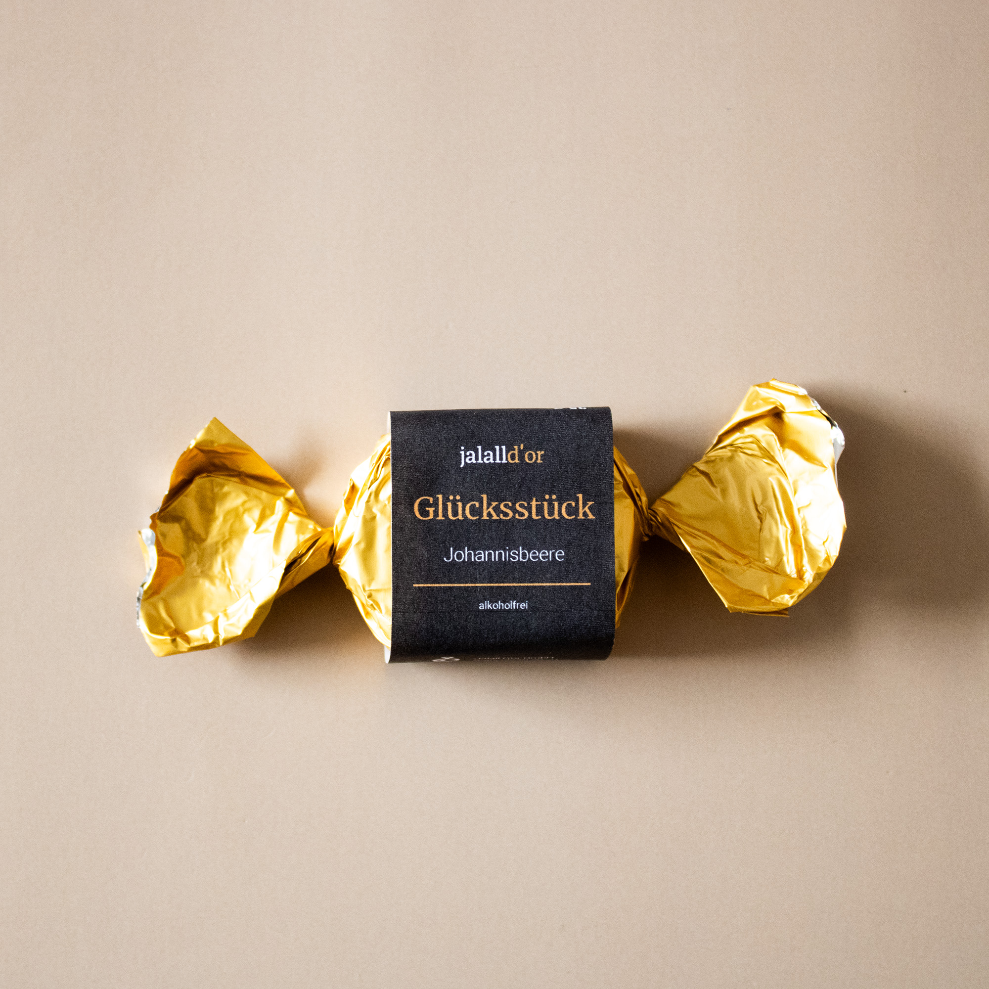 einzeln verpackte Praline in goldenem Papier mit schwarzer Banderole